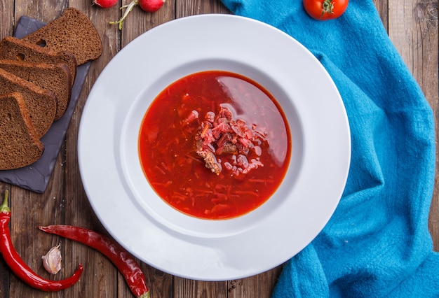 Beet soup in white plate with vegetables