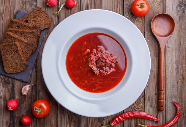 Beet soup in white plate with vegetables