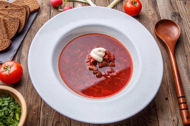 Beet soup in white plate with vegetables