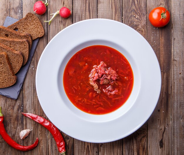 Beet soup in white plate with vegetables