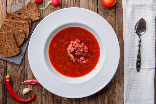 Beet soup in white plate with vegetables