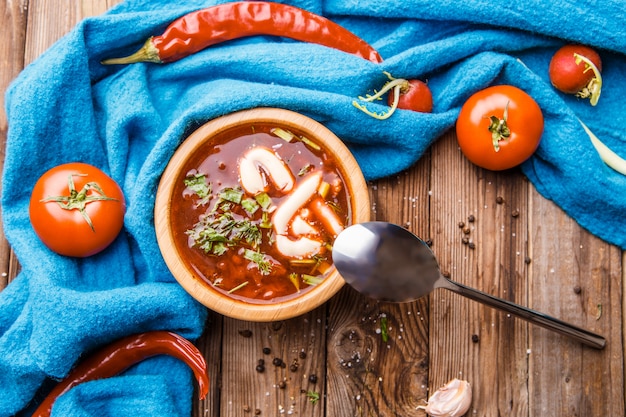 Beet soup in wooden plate with vegetables