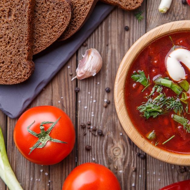 Beet soup in wooden plate with vegetables