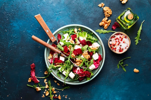 Beet summer salad with arugula radicchio soft cheese and walnuts on plate with fork dressing