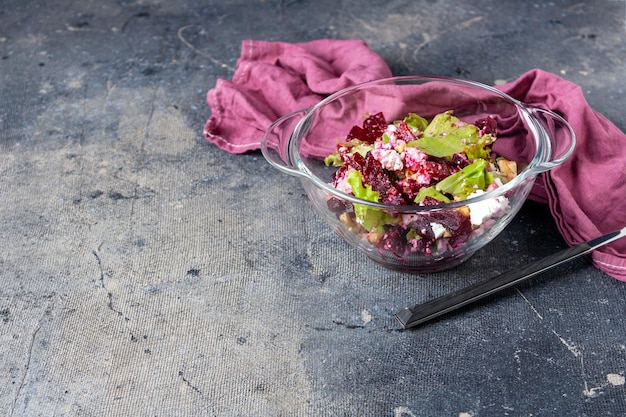 Beetroot and feta cheese salad in glass bowl fork on blue background copy space