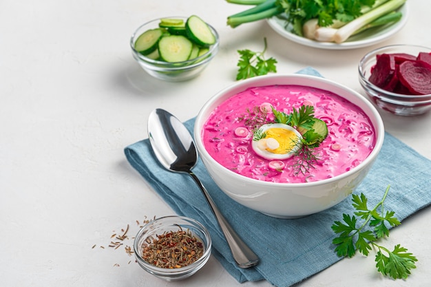 Beetroot soup with dill parsley and egg on a gray background