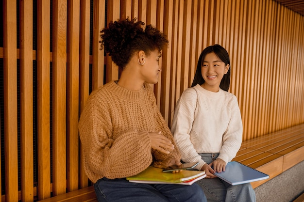 Before studying. Two girls sitting on a bench and talking