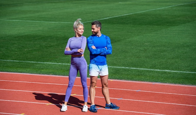 Before workout athlete and sportsman sport couple is good team fitness partners athletic man and woman relax after race male and female coach on stadium running track arena healthy lifestyle