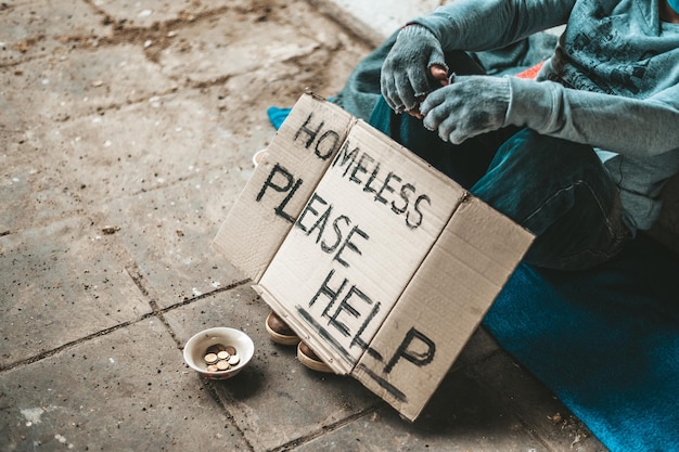 The beggars sat beside the street with a homeless message Please help and work with food