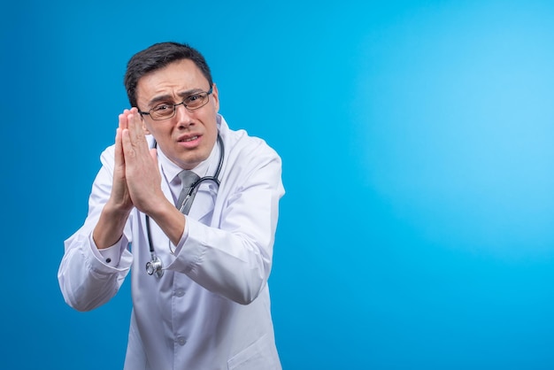 Begging physician with praying hands in studio