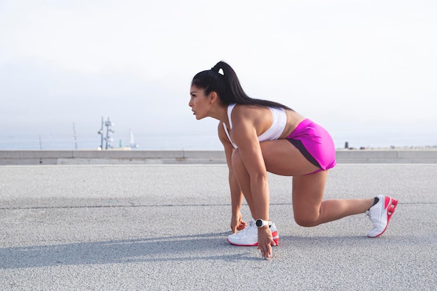 In the beginning Mixed race athlete woman sportswoman getting ready before running stretching her legs before training outside in the city