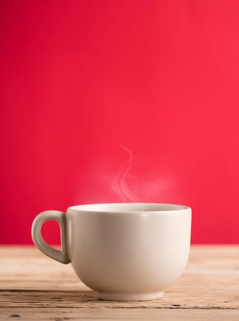 beige coffee cup with hot steam smoke  on wooden table red background