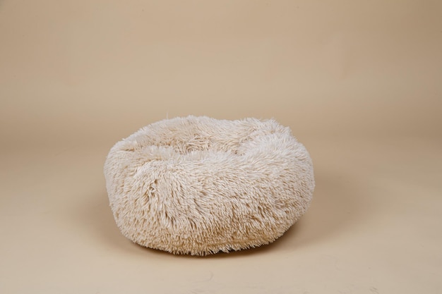 Beige dog bed in studio on brown background