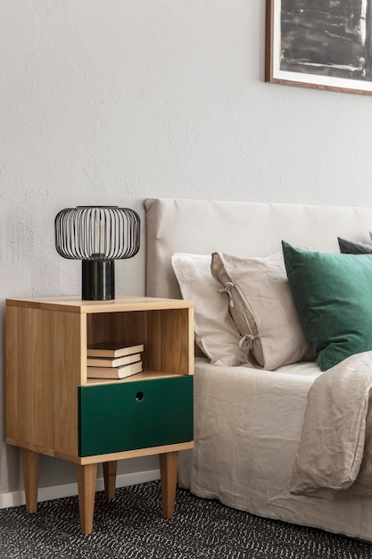 Beige and emerald bedroom design with modern lamp on wooden nightstand table