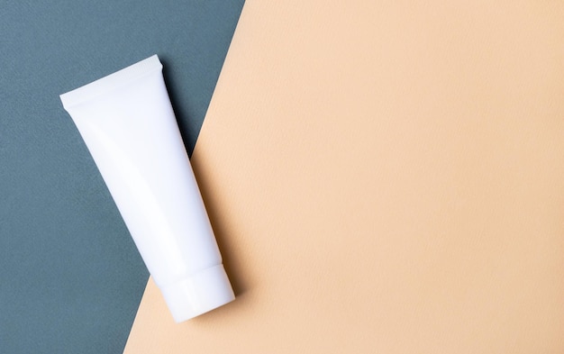 On a beige and green background a white tube for cream with a place to insert text Mockup View from above Copy space