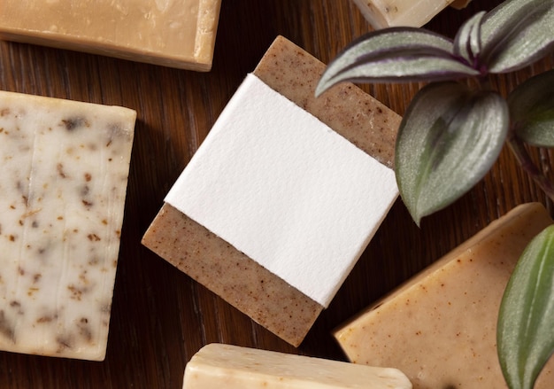 Photo beige handmade soap bars with blank label on wood near green plant top view packaging mockup