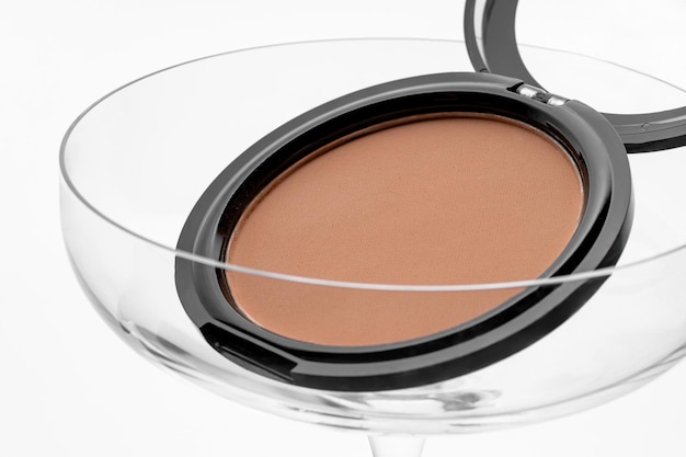 Photo beige makeup compact powder for face in a cocktail glass product presentation