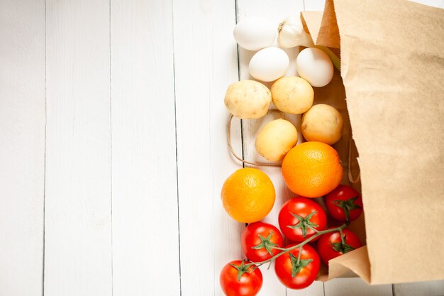 Beige paper bag on a wooden white, vegetables from the store