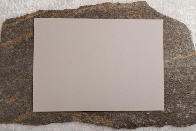 Beige paper business card mockup with stone on gray concrete background flat lay copy space