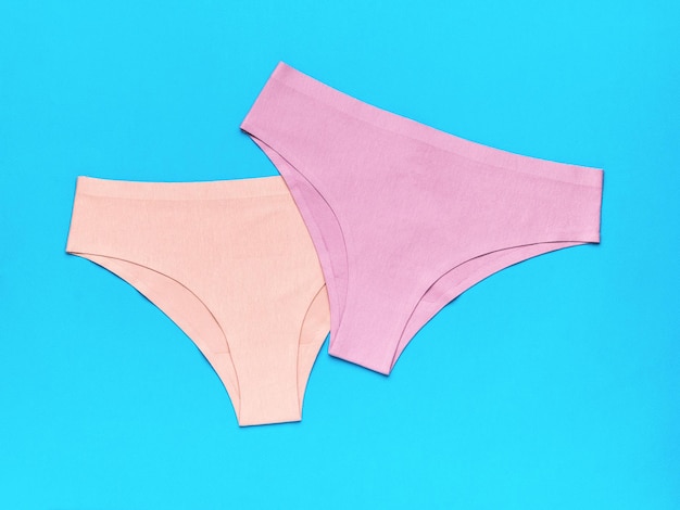 Beige and pink women's panties on a blue background The concept of women's underwear