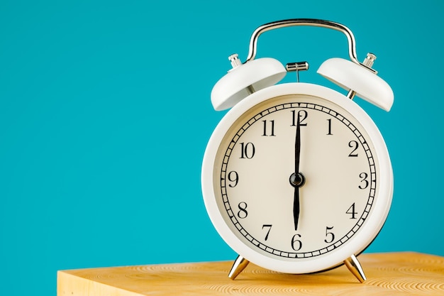 Beige vintage alarm clock on a blue background.