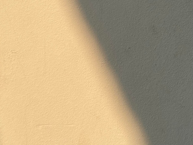 A beige wall with a shadow of a light on it.