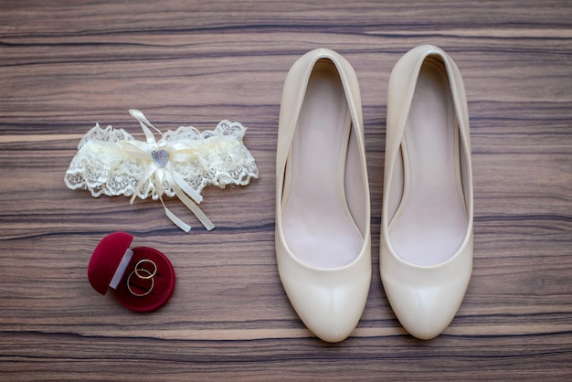 Beige wedding shoes white Bridal garter and wedding rings in red box on wooden background