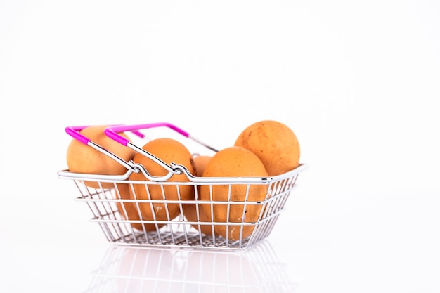 Beige, wild chicken eggs in a shopper's basket on a white background. Selective focus. Copy space.