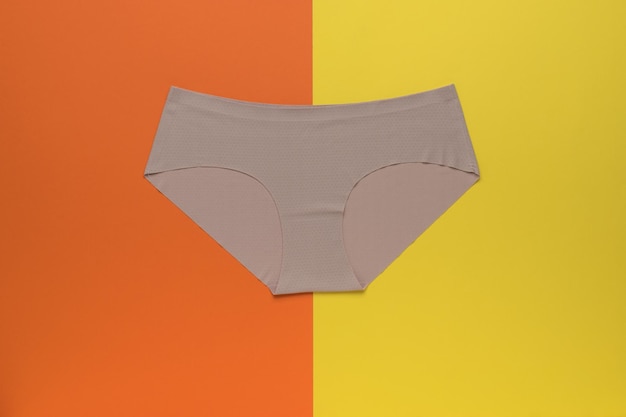 Beige women's seamless briefs on a yellow and orange background Women's underwear