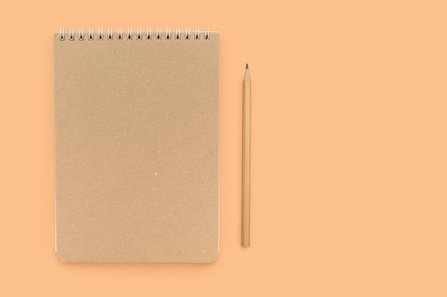 Beige working notebook and pencil for notes on a beige background Place for text