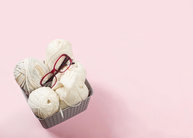 Beige yarn thread with knitting needles on a pink background for knitting