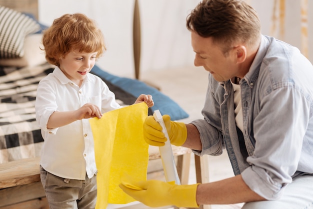 Being attentive. Delighted man sitting in semi position and wearing rubber gloves while preparing for cleaning