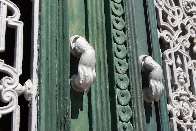 Beja, Alentejo, Portugal. Detail of a wooden door. Each gate knocker has the shape of a hand