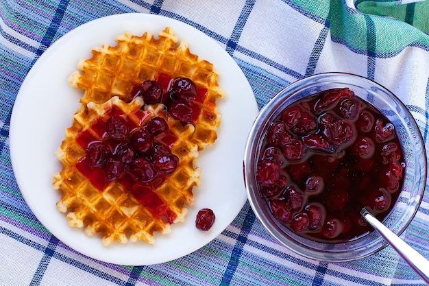 Belgian potato savory waffles with prosciutto cherry tomatoes basil leaves and hot tomato jam or spicy sauce Served breakfast brunch on light background