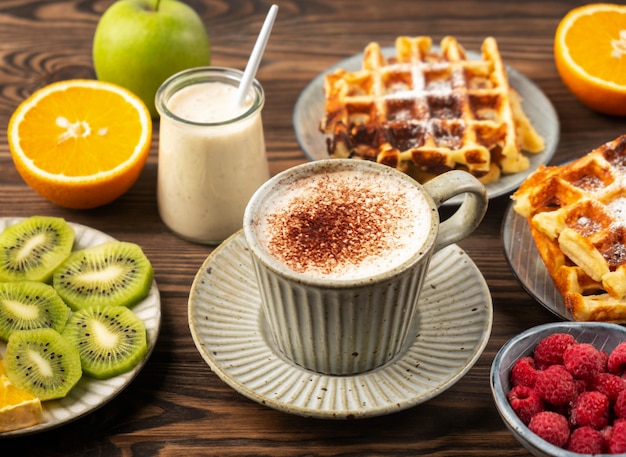 Belgian waffles, coffee, yogurt, fruits and berries on a wooden background, breakfast concept.