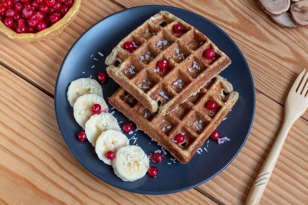 Belgian waffles with berries (red currants), bananas and coconut flakes