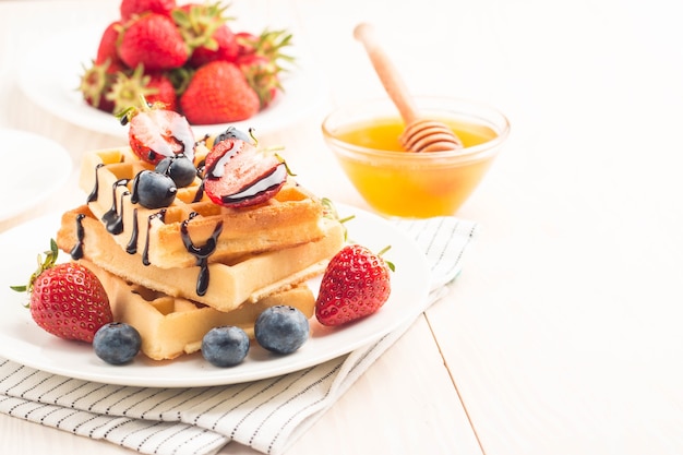 Belgian waffles with honey, chocolate, strawberry, blueberry, maple syrup and cream.