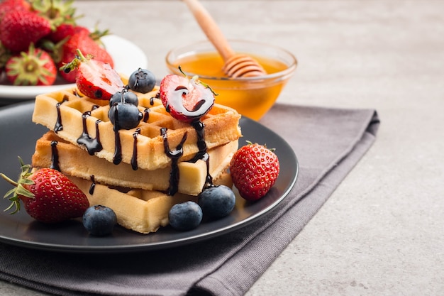 Belgian waffles with honey, chocolate, strawberry, blueberry, maple syrup and cream.