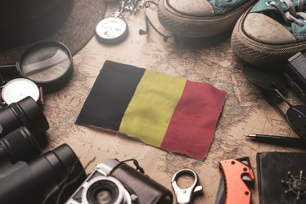 Photo belgium flag between traveler's accessories on old vintage map. tourist destination concept.