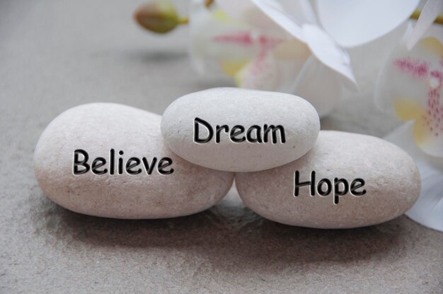 Photo believe dream and hope text engraved on zen stones believing concept