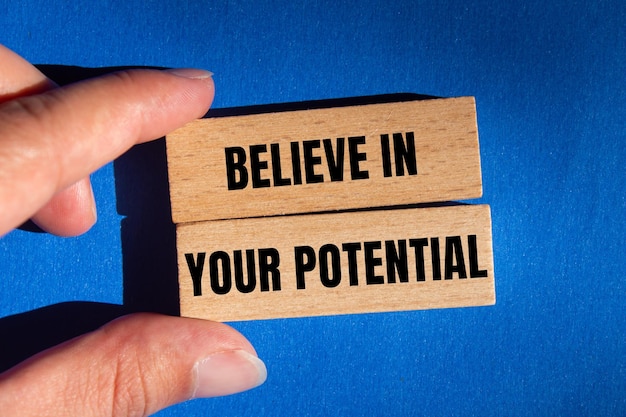 Believe in your potential message written on wooden blocks on blue background Conceptual believe in your potential symbol Copy space