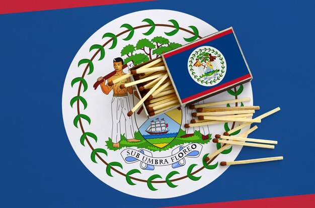 Belize flag  is shown on an open matchbox, from which several matches fall and lies on a large flag