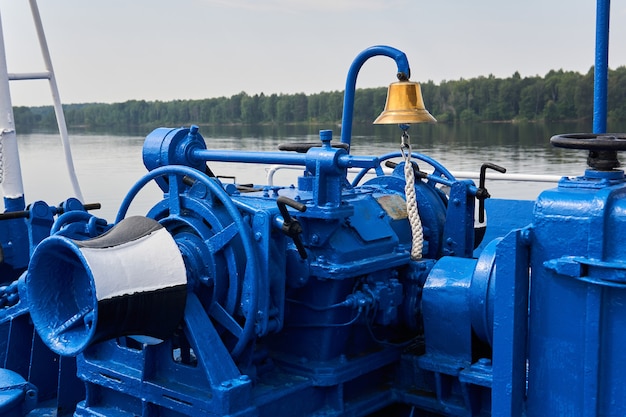 Photo bell, anchor windlass, capstan and other mechanisms, painted blue, on the foredeck of the river ship, close-up