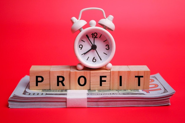 bell clock and money with the word profit. the concept of profit or income