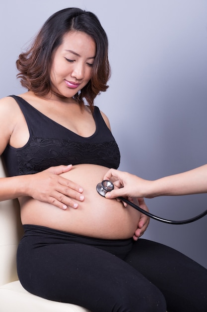 Belly of pregnant woman examined with a stethoscope