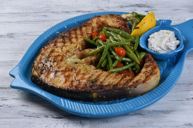 Beluga steak with vegetables and sauce, grilled fish steak, seafood, top view