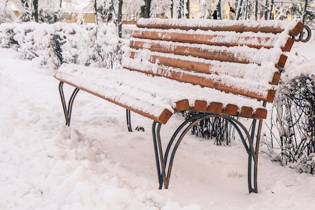 Bench covered with snow in snowbound city in winter. Winter time