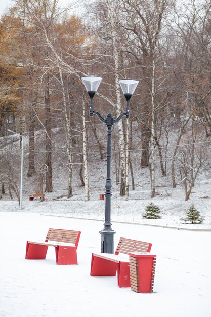 A bench with red benches in front of a lamp post with two lights on it.