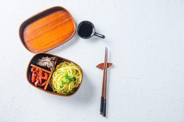 Bento beef noodles lunch box top view space for text on white table.