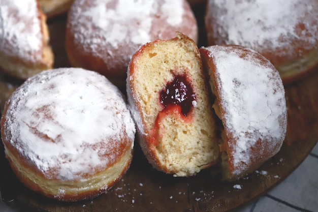 Berliner donuts in powdered sugar on a wooden tray